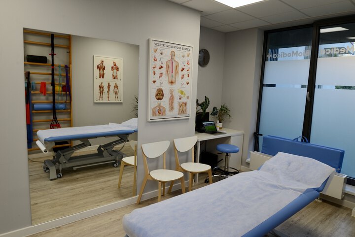 Wnętrze gabinetu fizjoterapeutycznego z wyposażeniem takim jak: łóżko, krzesła, piłki i wałki